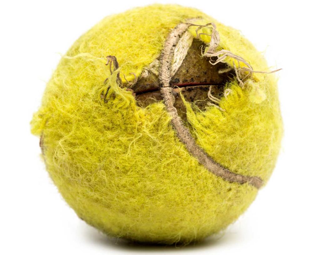 Vom Hund zerkauter Tennisball mit deutlichen Schäden an der Hülle. Vom Hund zerkauter Tennisball. Gefährliche Tennisbälle.